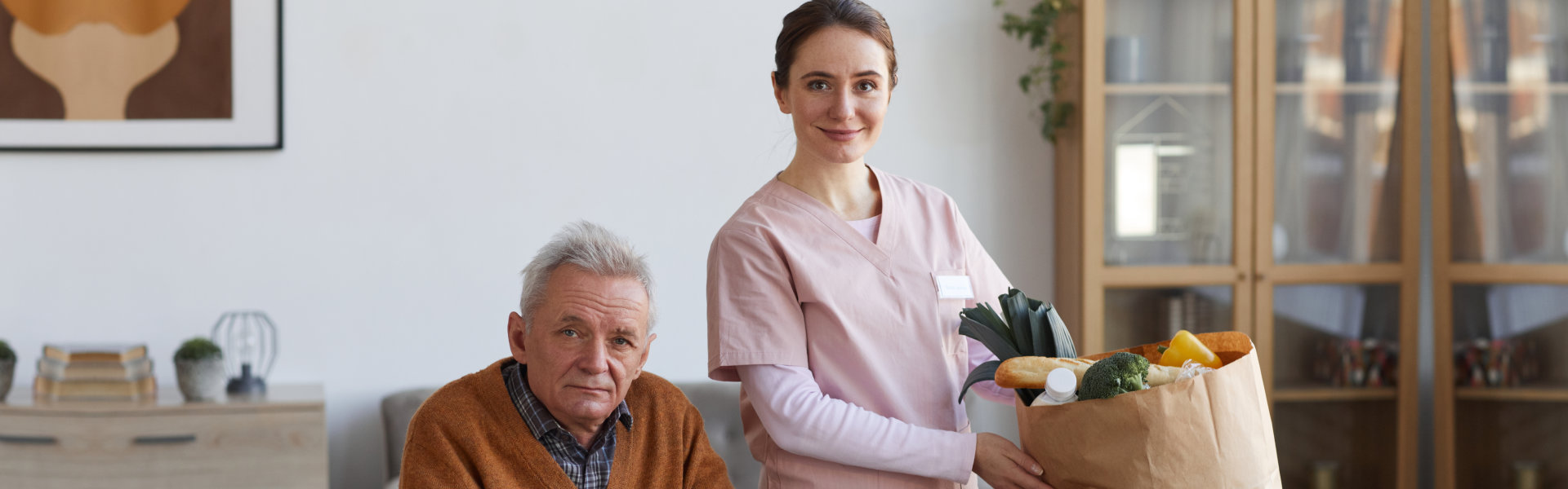 Caregiver holding groceries with senior man